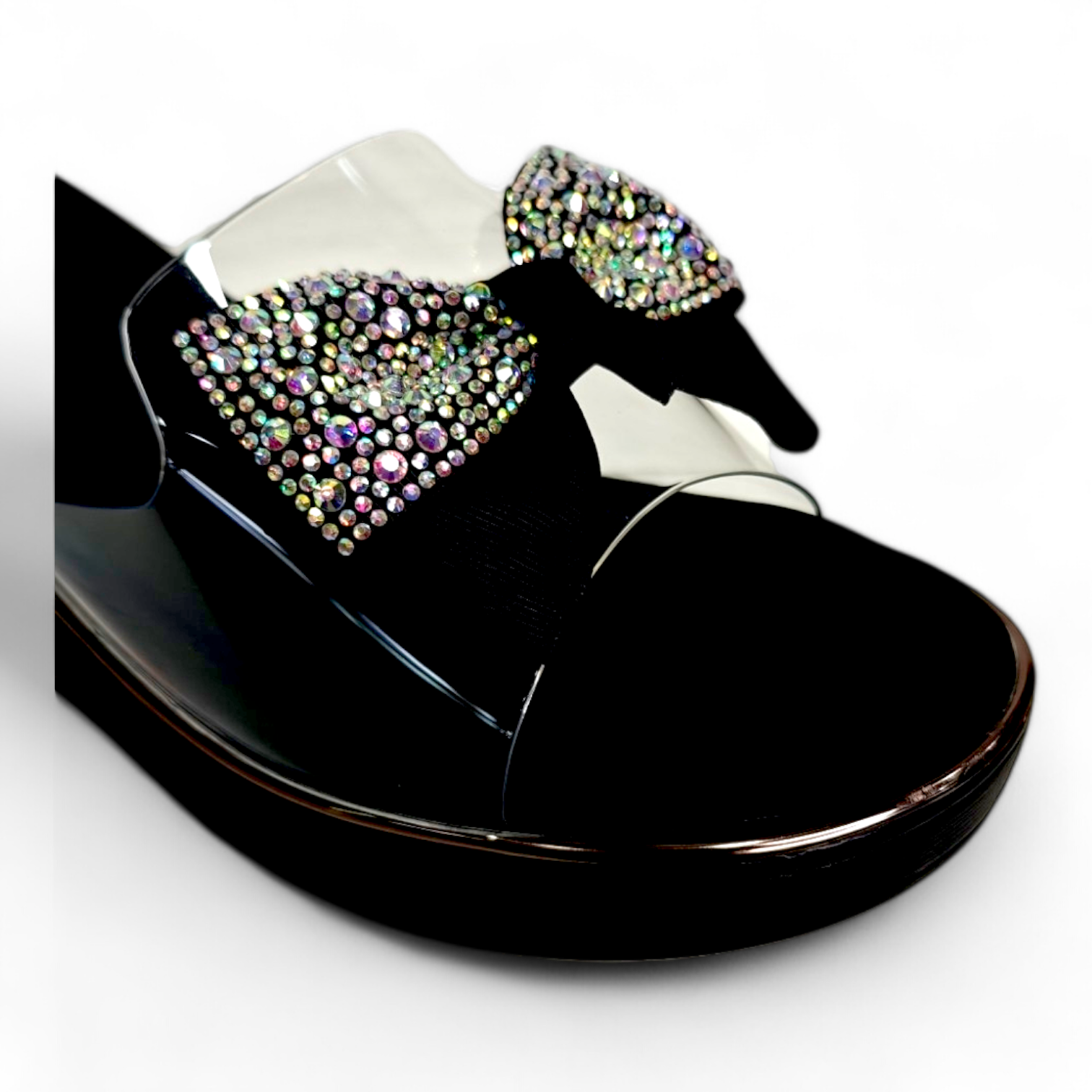 Close-up of embellished bow detail on transparent belt of black wedge heel footwear