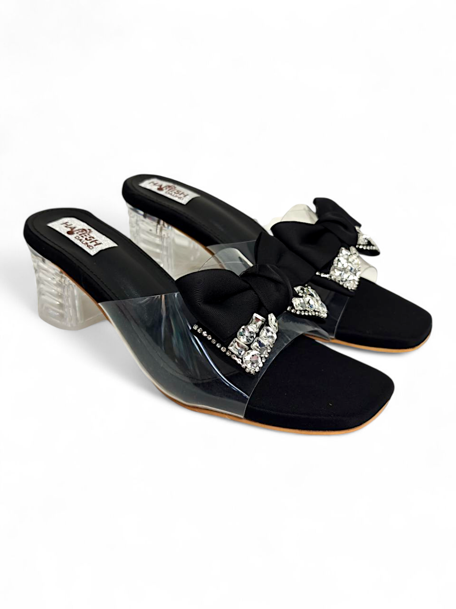 Top angle showing transparent strap and bow embellishment on black sandals