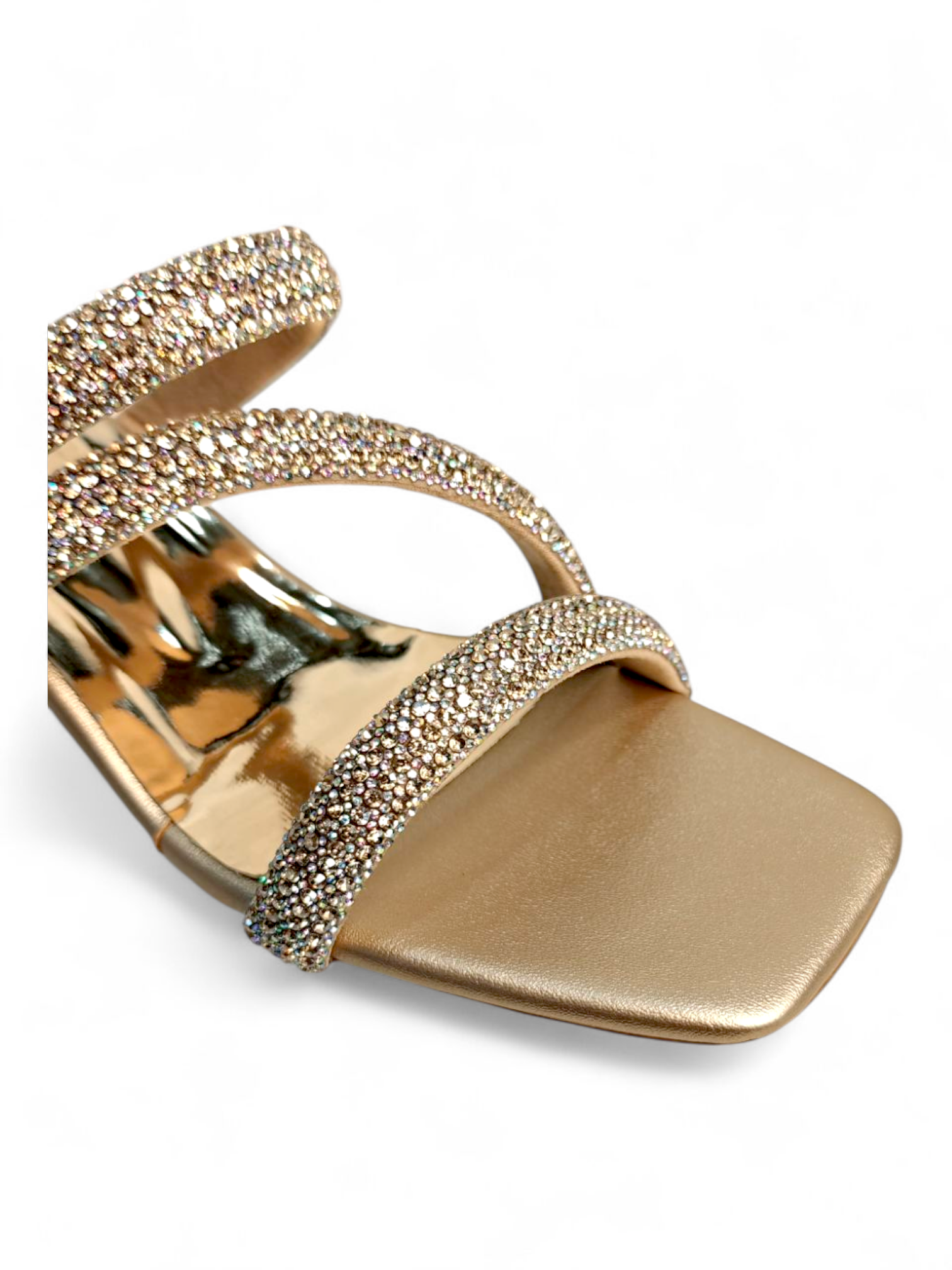Close-up of sparkling crystal embellishments on gold triple strap sandals
