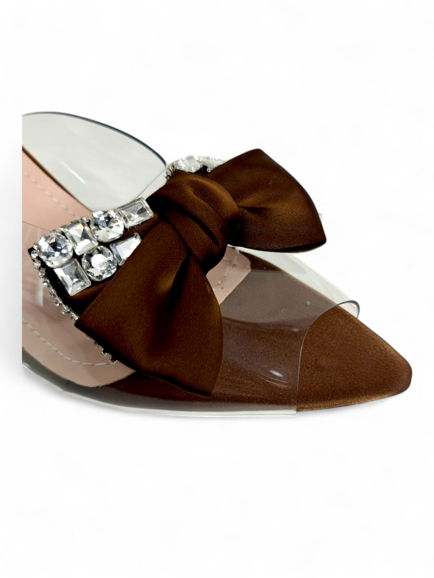Close-up of crystal detailing and brown bow on transparent strap sandals