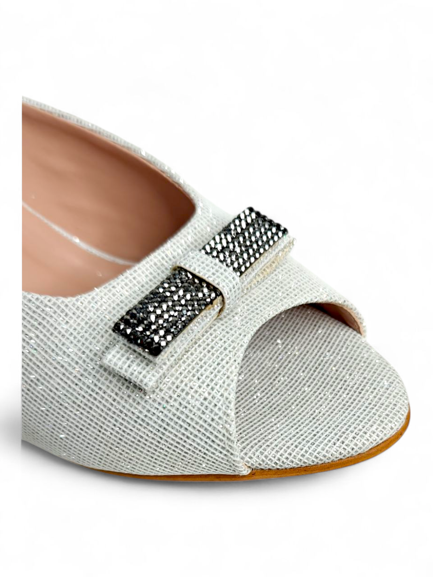Close-up of buckle embellishment on white textured peep-toe heel sandals