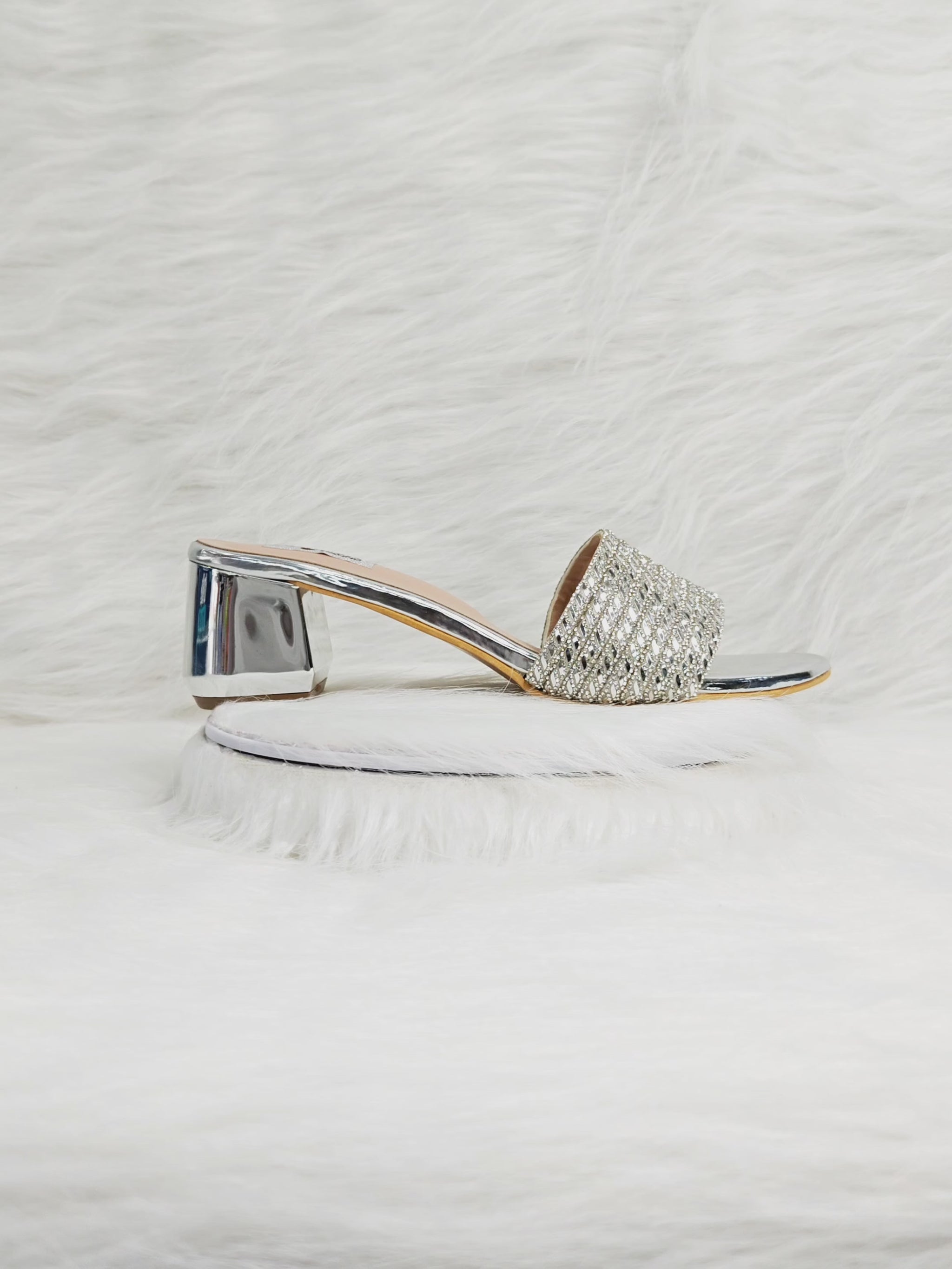 A model walking in silver embellished block heels, showing the sparkle of the strap and comfort of the cushioned sole, styled with Indian festive outfits.