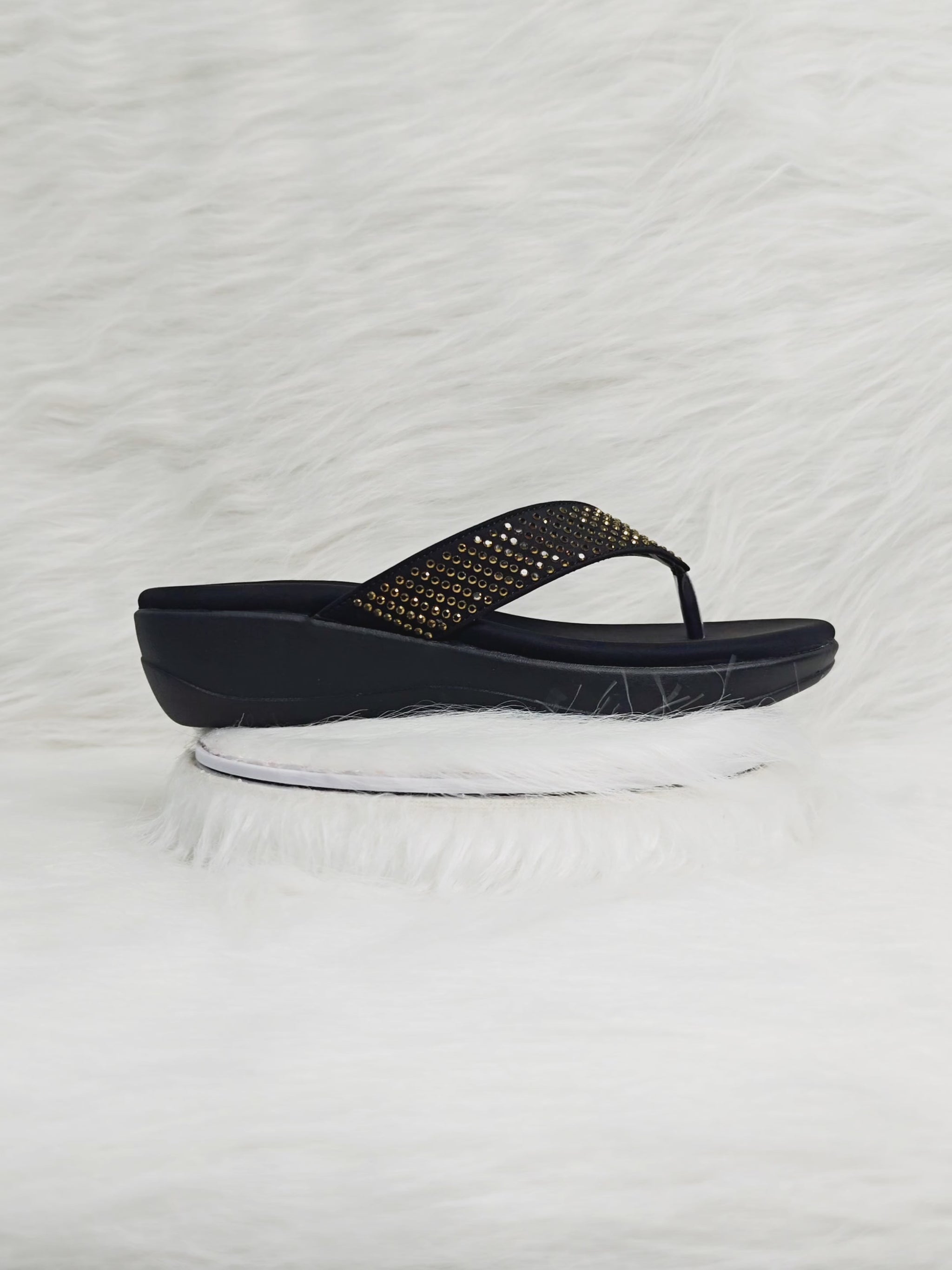 A 360-degree view of elegant black wedge thong sandals for women, featuring gold embellishments on the upper strap and a cushioned footbed. The video shows the footwear from multiple angles, highlighting comfort, shine, and a durable wedge sole suitable for festive and everyday wear.
