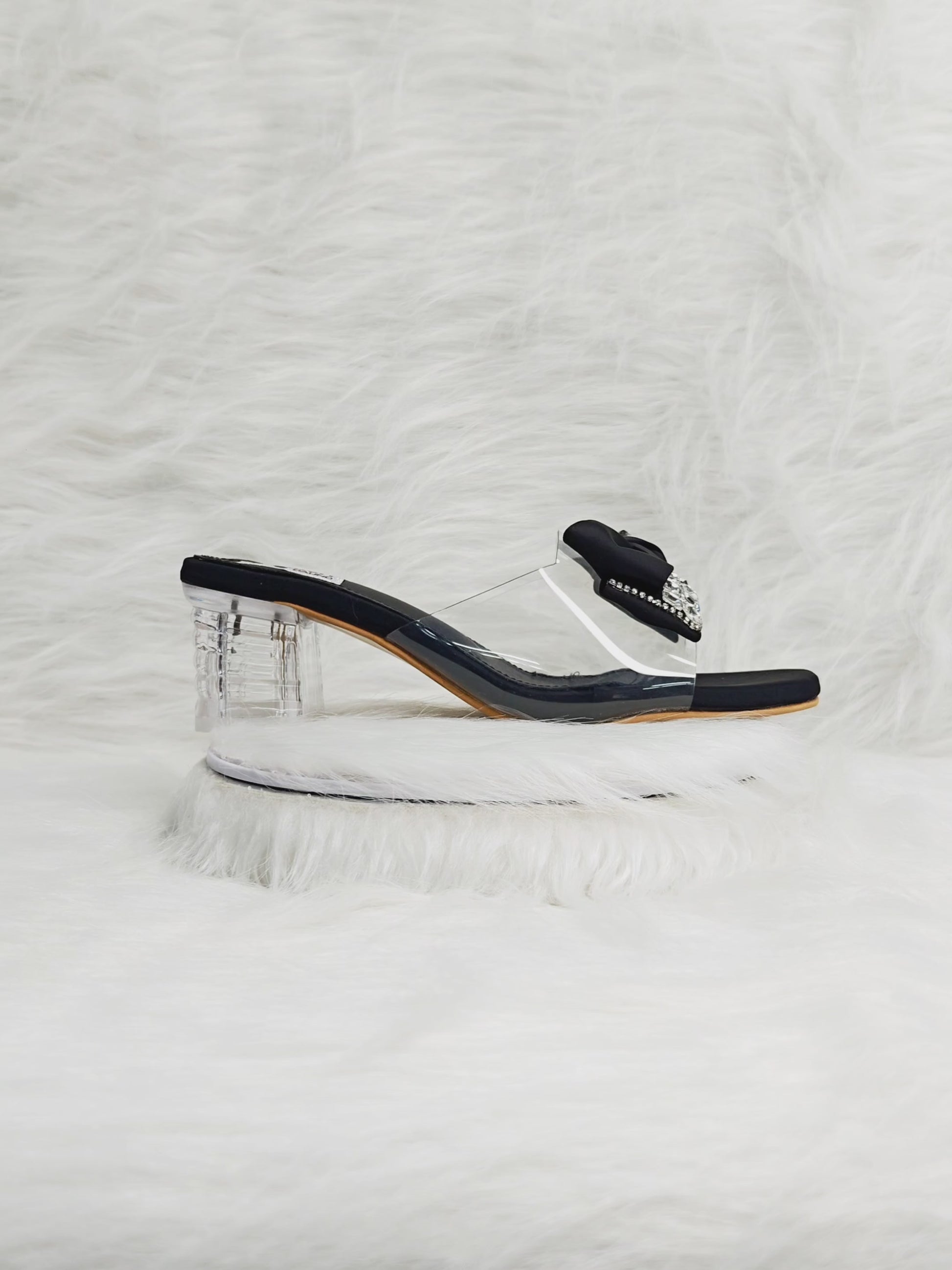 360 degree rotation of black bow embellished clear block heel sandals with transparent strap