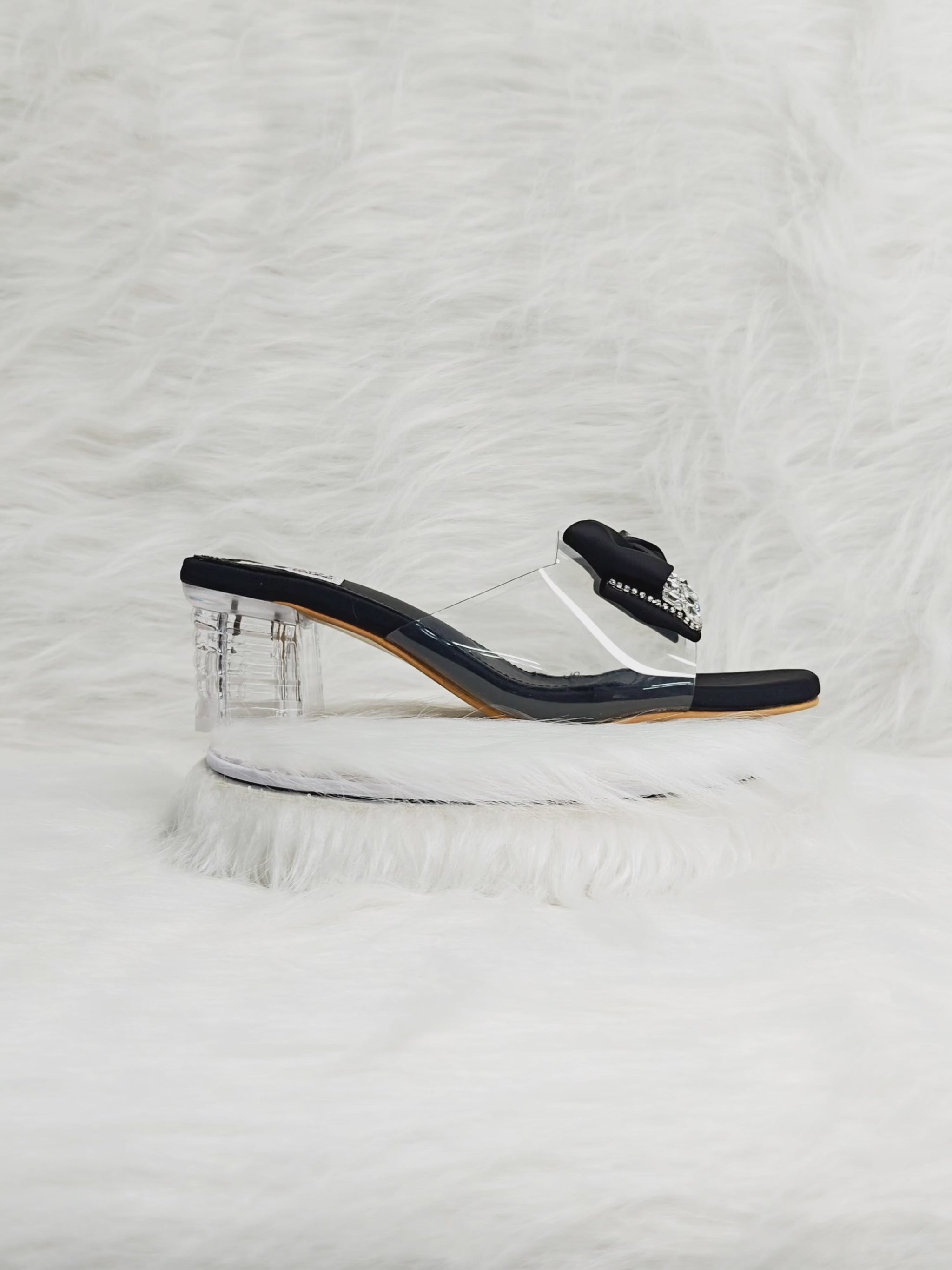 360 degree rotation of black bow embellished clear block heel sandals with transparent strap