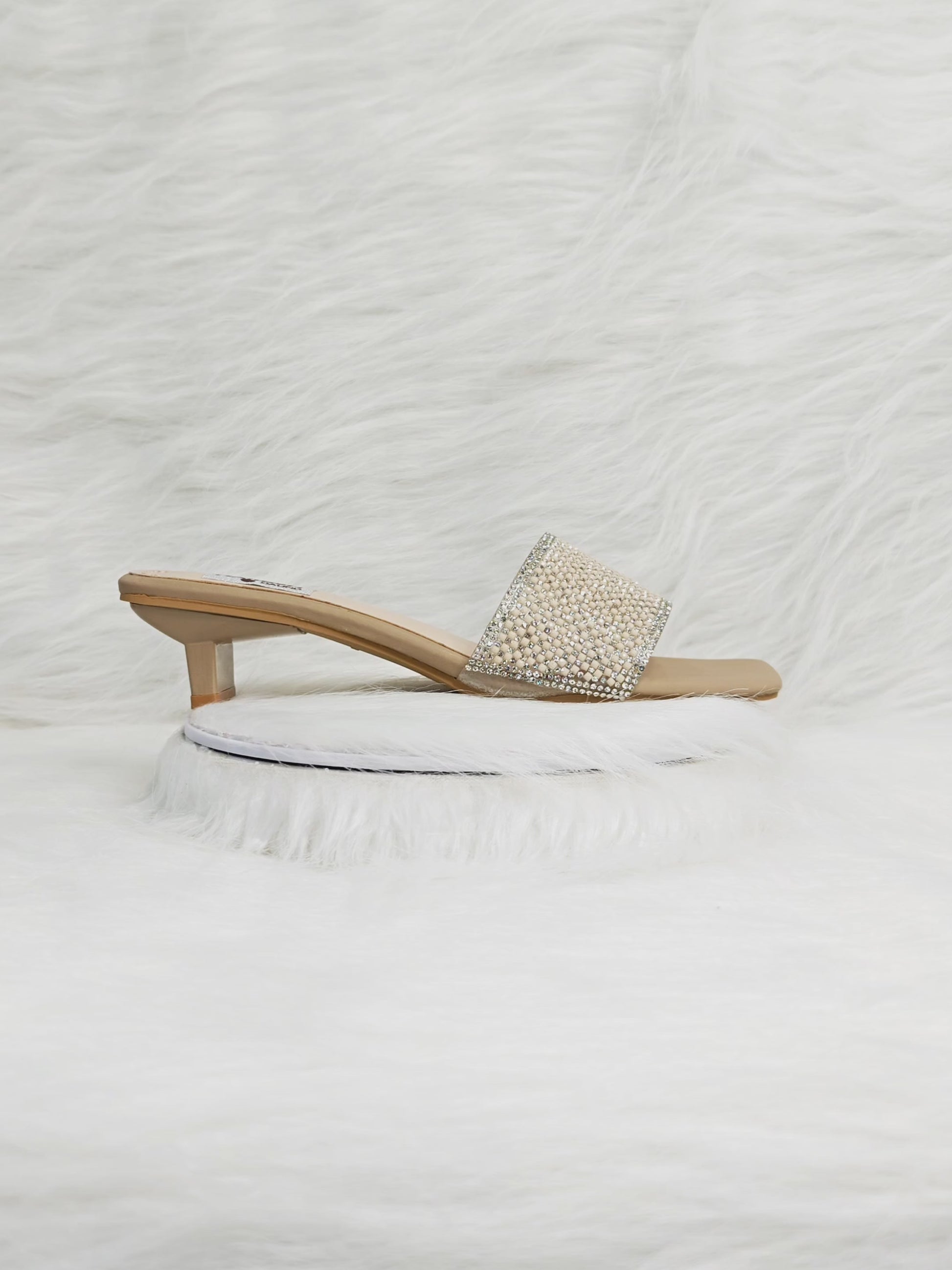 A close-up 360° video of beige crystal embellished heel sandals for women, highlighting the sparkling crystal strap, cushioned insole, and stylish block heel. Ideal for party, wedding, and festive wear.